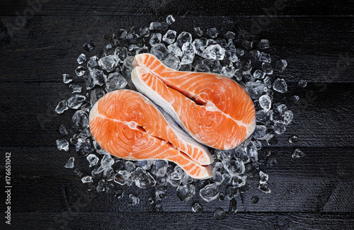 Salmon steak on ice on black wooden table top view