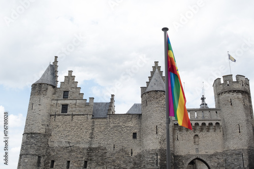 Hetsteen Castle in Antwerp, Belgium on a cloudy day with the LGBT gay rainbow flag in the foreground. Het Steen Castle in Antwerp.