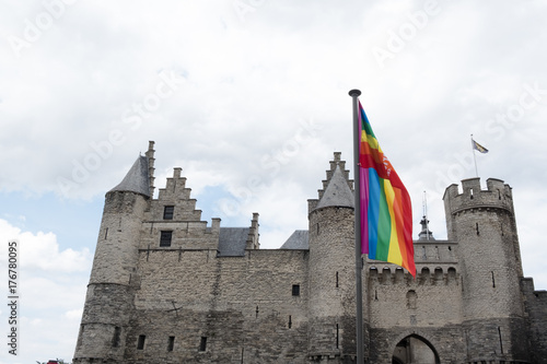 Het Steen Castle in Antwerp, Belgium on a cloudy day with the gay rainbow flag in the foreground.