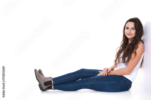 Junge Frau sitzt vor weißem Hintergrund