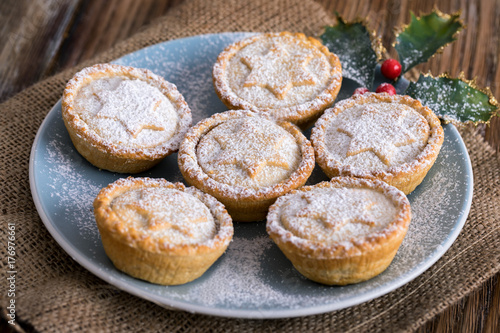 Traditional, british Mince Pies on a plate decorated with a mistletoe