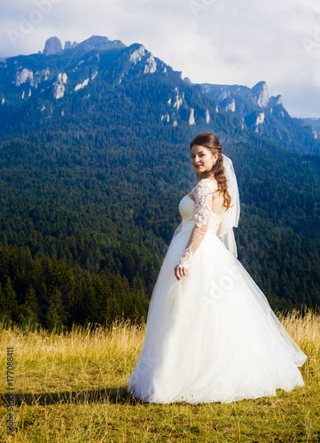 young and beautiful bride in wedding dress posing in nature