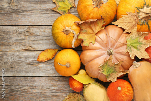Orange pumpkins with dry leafs on grey wooden table