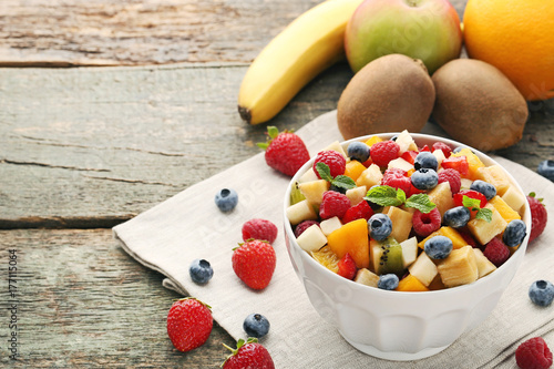 Fresh fruit salad in bowl on grey wooden table