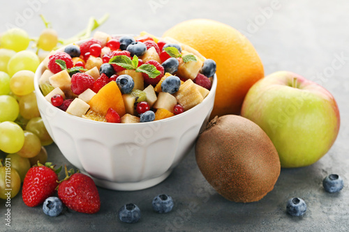Fresh fruit salad in bowl on grey wooden table
