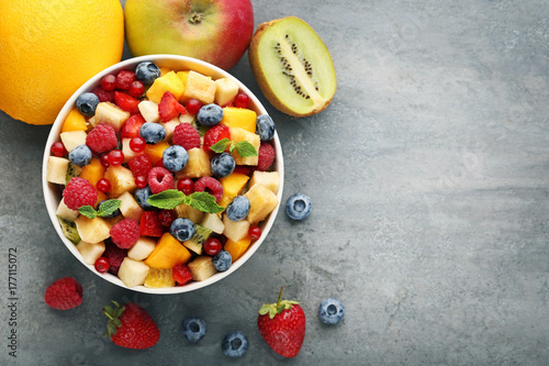 Fresh fruit salad in bowl on grey wooden table