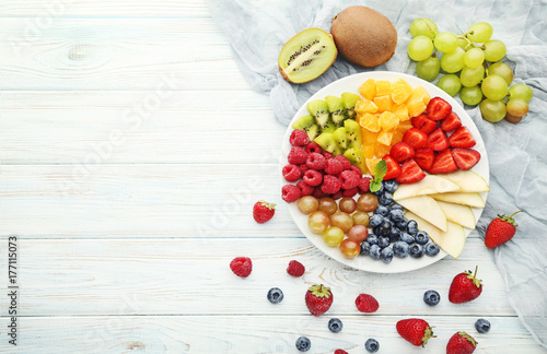 Fresh fruits in plate on wooden table
