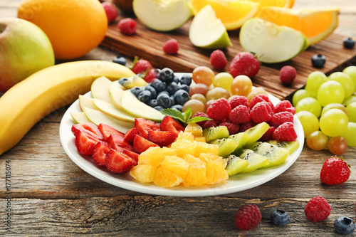 Fresh fruits in plate with cutting board on wooden table