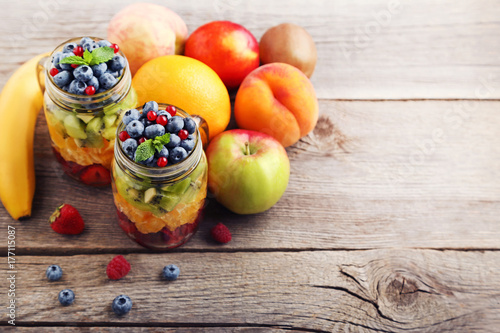 Fresh fruit salad in jars on grey wooden table