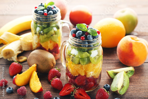 Fresh fruit salad in jars on brown wooden table