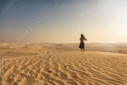 Verschleierte Frau steht in der Wüste von Katar auf einer Düne