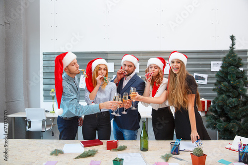 Plakat Młodzi szczęśliwi przyjaciele świętuje nowego roku na zamazanym tle. Przyjęcie gwiazdkowe z Santa kapeluszy pojęciem.