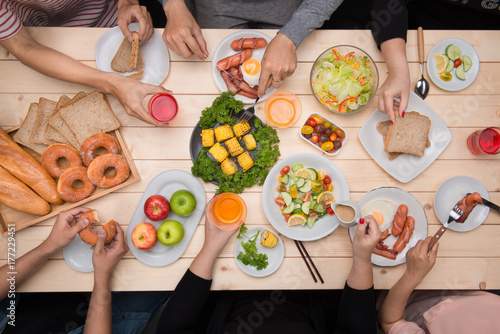 Zdjęcie XXL Cieszyć się kolacją z przyjaciółmi. Odgórny widok grupa ludzi ma gościa restauracji wpólnie podczas gdy siedzący przy drewnianym stołem