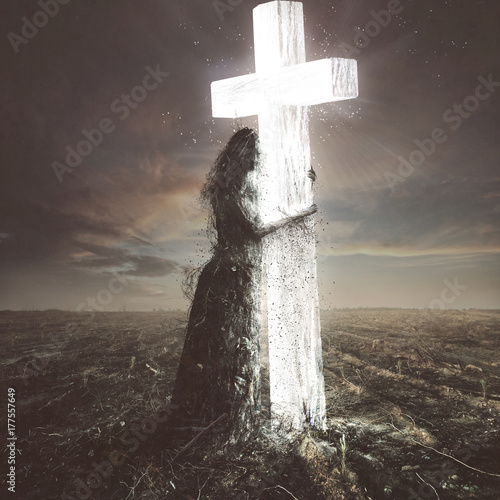 Woman made of dirt clings to the cross