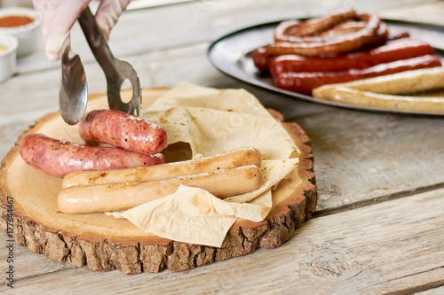 Plakat Szef kuchni wprowadzenie grillowane kiełbaski na naturalne drewno. Różne kiełbaski i lavash na drewnianym talerzu. Pyszne europejskie jedzenie.