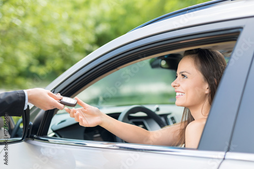A young beautiful woman receive the keys to the new car.