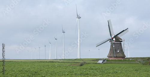 Zdjęcie XXL stary wiatrak goliath w roodeschool w holenderskiej prowincji groningen między rzędem nowoczesnych turbin wiatrowych