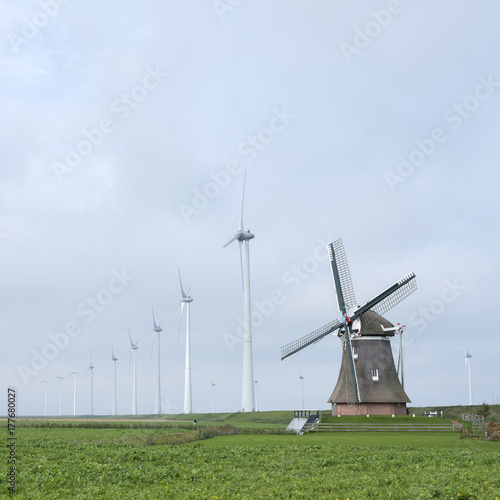 Zdjęcie XXL stary wiatrak goliath w roodeschool w holenderskiej prowincji groningen między rzędem nowoczesnych turbin wiatrowych