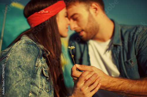 Happy young couple holding flower in hands in nature. Focus on hands and flower.