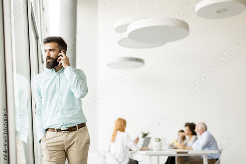 Young bisinessman talking over the movile phone by windows in office