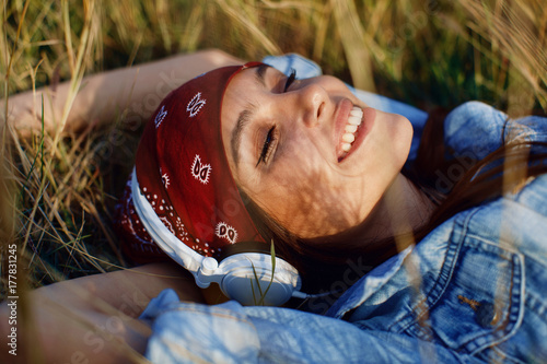 Closeup of young woman listens to music and lying in the meadow