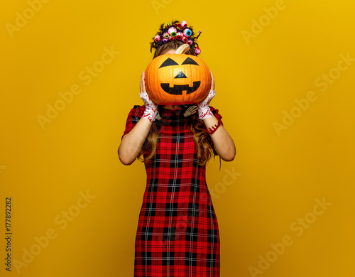 woman with halloween pumpkin in front of face isolated on yellow