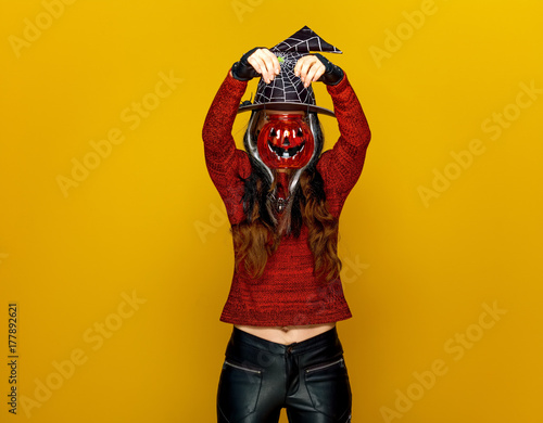 young woman holding jack-o-lantern in front of face
