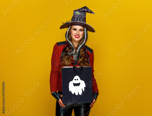 happy woman isolated on yellow with Halloween shopping bag