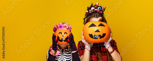 mother and child holding jack-o-lantern pumpkins in front of faces