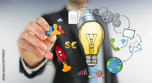 Businessman drawing a lightbulb with a pen with multimedia icons