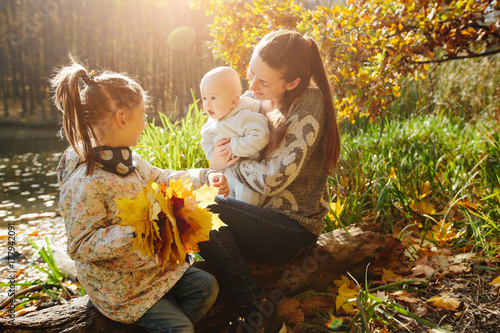 Happy family concept. Mother and children having fun in the autumn forest next to a lake. Motherhood concept
