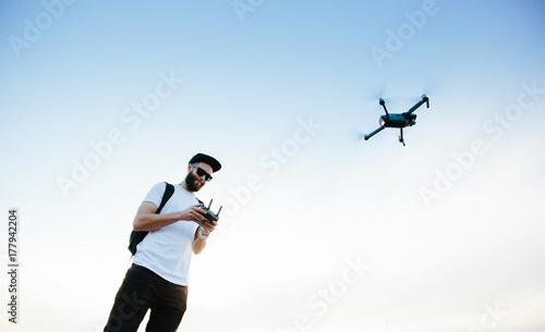 Man controlling a dron via a a controller and flying. man playing with the drone