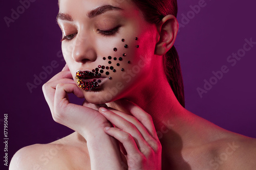 Young beautiful girl with blue eyes. Bright makeup, red lipstick. Art, rhinestones on the lips and face