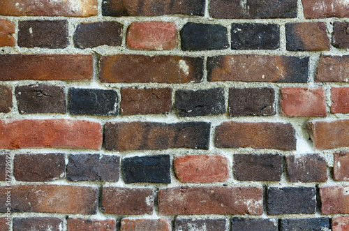 part of old brick wall built of bricks of different colors