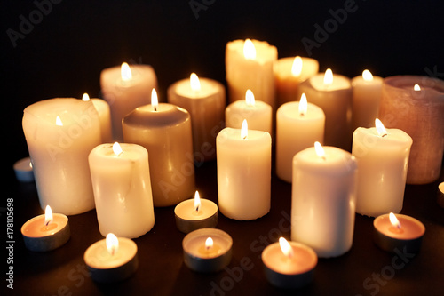 candles burning in darkness over black background