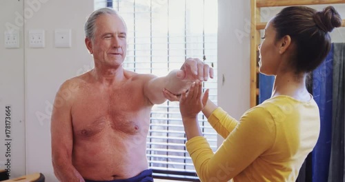 Physiotherapist giving hand massage to senior man 