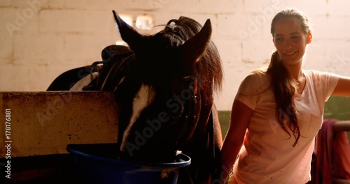 Woman standing with the horse in the stable 