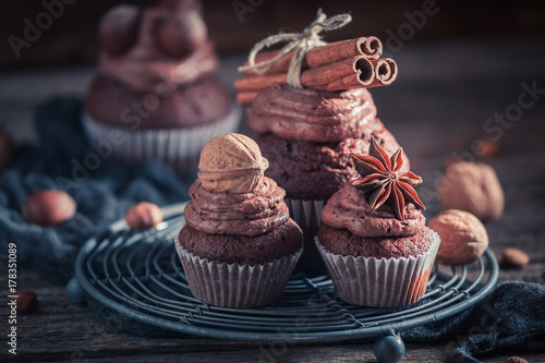 Tasty chocolate cupcake with nuts and brown cream