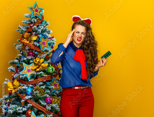 stressed woman near Christmas tree with pack of pills