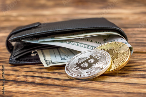 Closed wallet with dollar bills and bitcoins on the wooden table. Business concept.