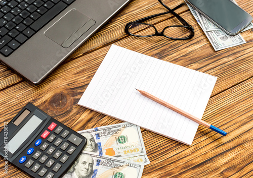 Working space with blank notepad, laptop, calculator, glasses, smartphone and money. Business concept.