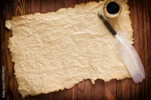 quill with inkstand on vintage paper background and wood table