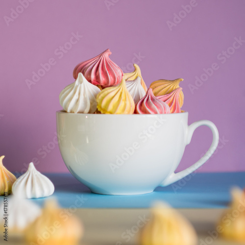 Dessert with meringue, a lot of colorful meringues in the tea Cup