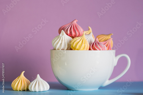 Dessert with meringue, a lot of colorful meringues in the tea Cup