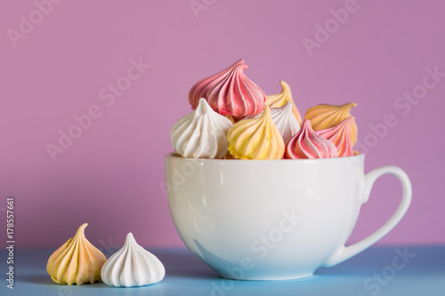 Dessert with meringue, a lot of colorful meringues in the tea Cup