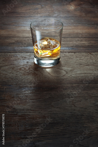 close up view of  glass with ice and whiskey on wooden background