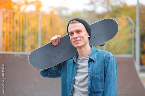 Zdjęcie XXL Młody deskorolkarz pozuje z deskorolka w skatepark. Pojęcie sportu.