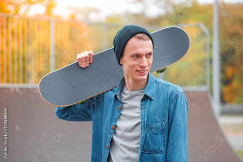 Zdjęcie XXL Młody deskorolkarz pozuje z deskorolka w skatepark. Pojęcie sportu.