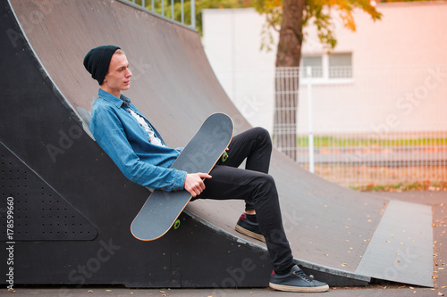 Zdjęcie XXL Młody deskorolkarz pozuje z deskorolka w skatepark. Pojęcie sportu.