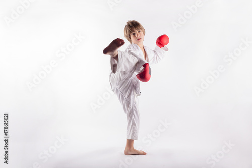 Plakat Chłopiec nosi kimono i czerwone rękawice bokserskie pokazano exercices